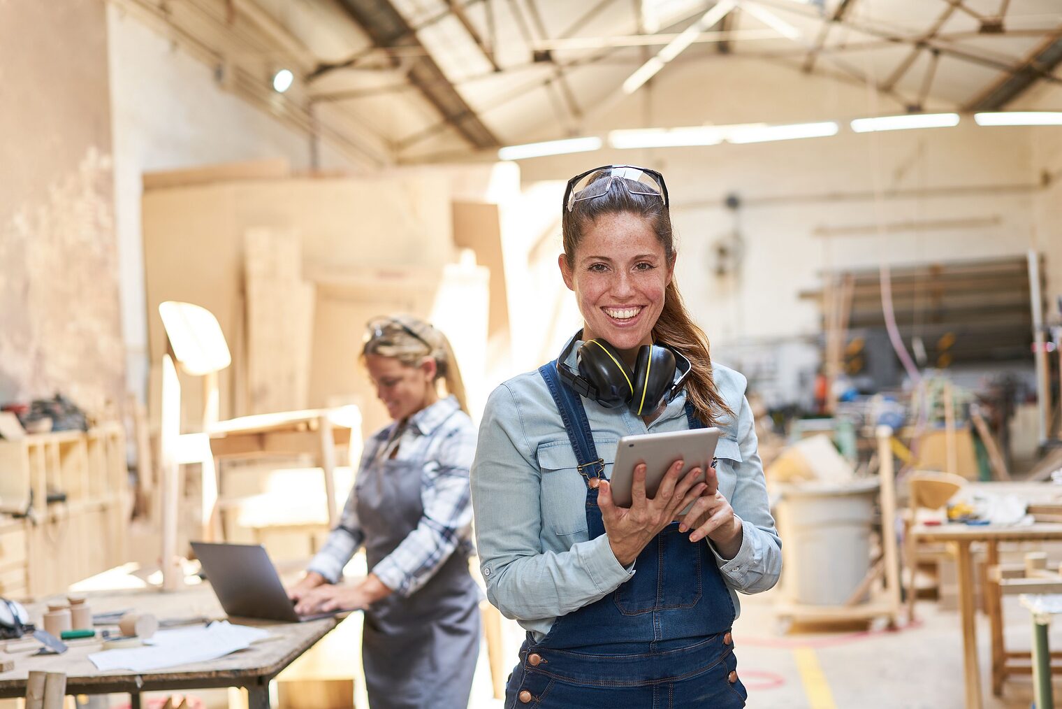 Lächelnde Handwerker Frau in der Tischlerei Werkstatt mit Tablet Computer Schlagwort(e): Frau, Handwerker, Tablet, Computer, online, Kommunikation, Werkstatt, Planung, planen, Schreinerei, Betrieb, Kundenservice, freundlich, Handwerksbetrieb, Terminplanung, lächeln, positiv, Auftrag, Kundengespräch, Organisation, Terminvereinbarung, Tischlerei, Schreiner, Tischler, Holz, digital, mobil, Laptop, Holzarbeit, Handwerk, Zimmerei, Arbeit, Beruf, Bau, Arbeiter, Holzarbeiter, Holzverarbeitung, weiblich, jung, arbeiten, Leute, mittelständisch, Mittelstand